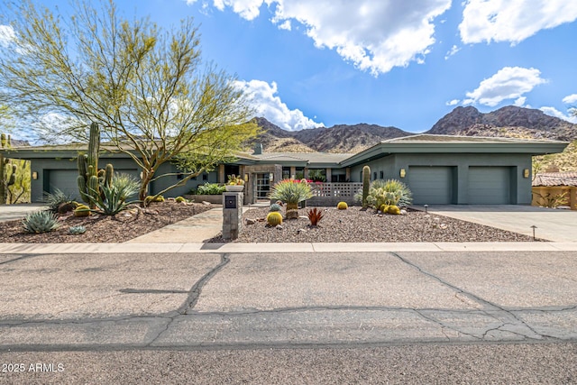 view of front of house with stucco siding, an attached garage, a mountain view, and driveway