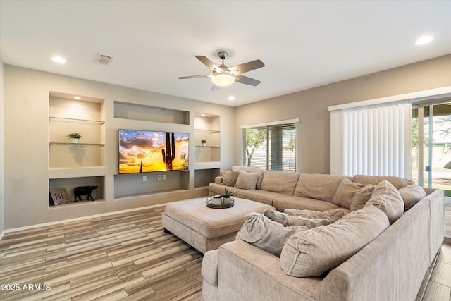 living area with a healthy amount of sunlight, light wood-style flooring, built in shelves, and visible vents