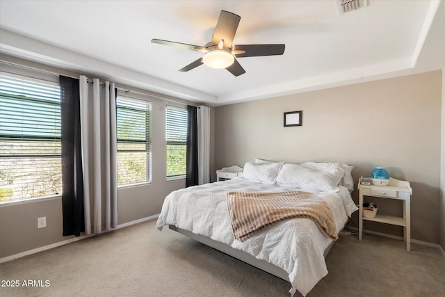 bedroom featuring carpet, a raised ceiling, visible vents, and multiple windows