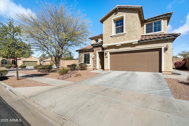 mediterranean / spanish home featuring driveway, a garage, a tiled roof, fence, and stucco siding