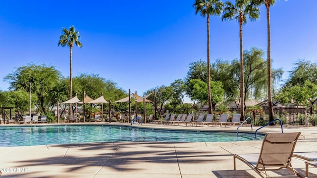 pool with a patio area and fence