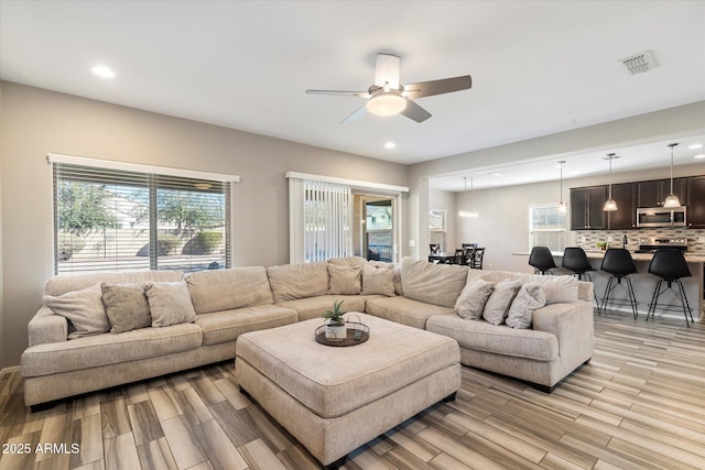 living area with a ceiling fan, recessed lighting, visible vents, and light wood-style floors