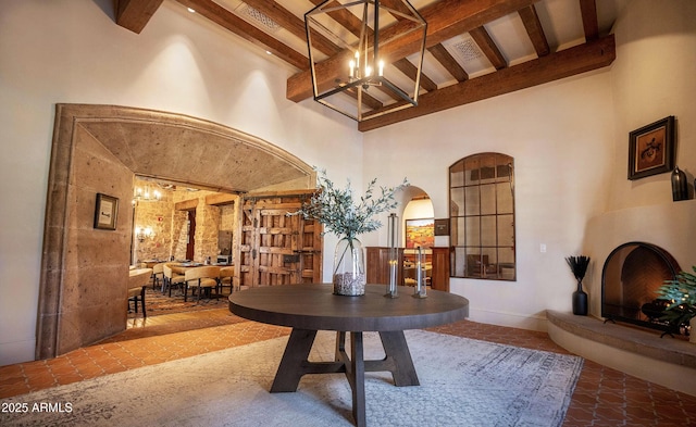 interior space featuring arched walkways, a high ceiling, an inviting chandelier, and beam ceiling