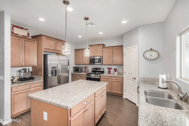 kitchen with pendant lighting, sink, stainless steel appliances, a center island, and light stone countertops