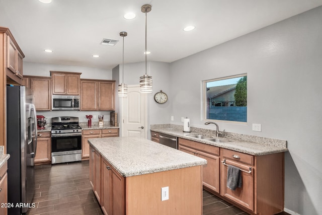 kitchen featuring pendant lighting, sink, appliances with stainless steel finishes, light stone countertops, and a kitchen island