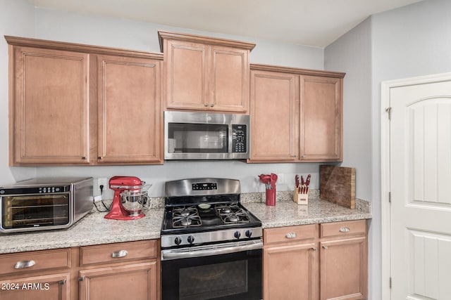 kitchen featuring stainless steel appliances and light stone counters