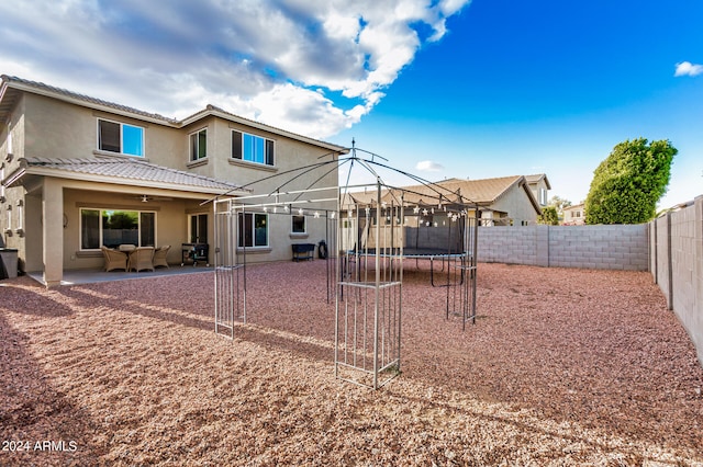 back of property featuring a trampoline and a patio area