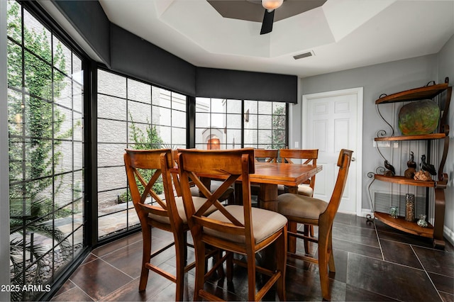 dining space featuring a tray ceiling, baseboards, visible vents, and ceiling fan