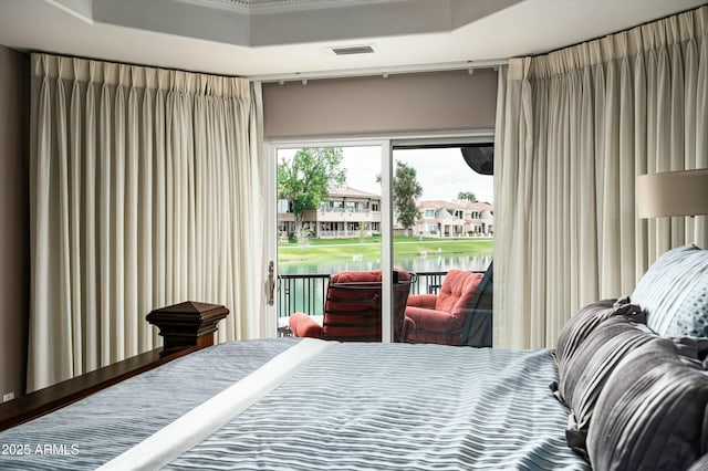 bedroom with a tray ceiling, access to outside, and visible vents