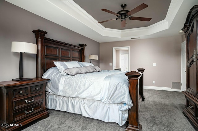 bedroom with visible vents, ornamental molding, baseboards, dark colored carpet, and a raised ceiling