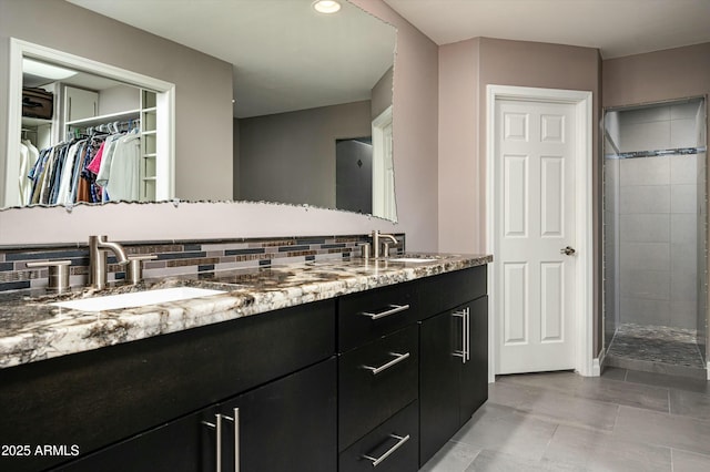 full bath with a sink, backsplash, a stall shower, and double vanity