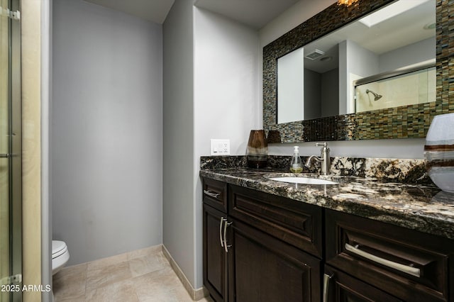 full bathroom with visible vents, toilet, a stall shower, baseboards, and vanity