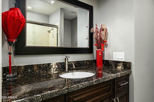 bathroom with visible vents, vanity, and a shower with shower door