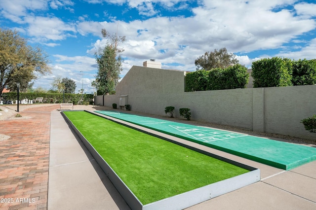 view of home's community with shuffleboard and fence