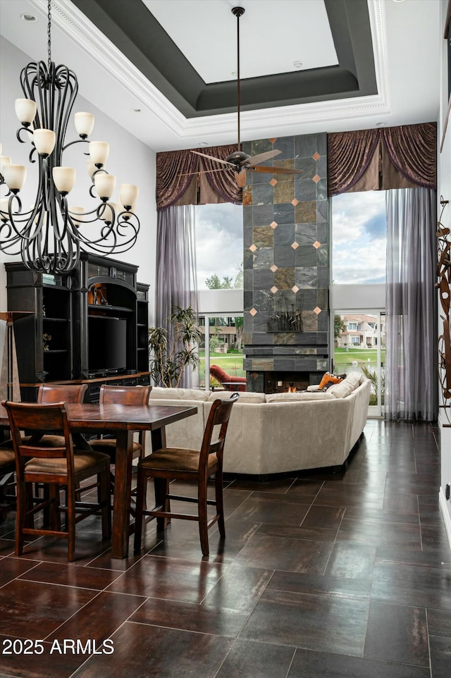 dining room with an inviting chandelier, a tray ceiling, and a tile fireplace