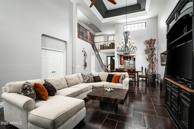 living room featuring a tray ceiling, ceiling fan with notable chandelier, a towering ceiling, and ornamental molding