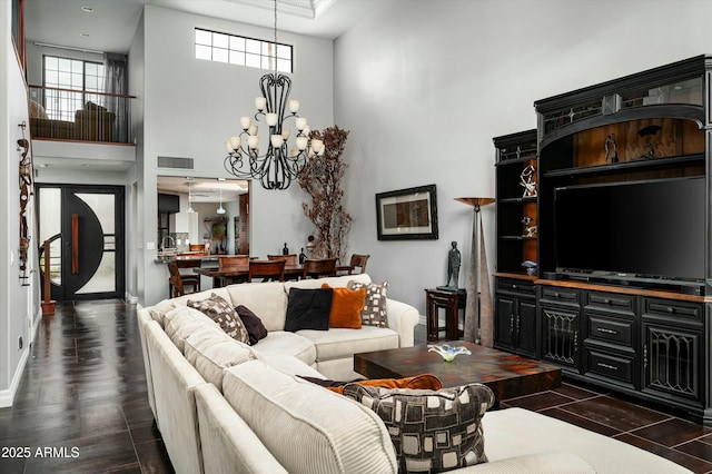 living area featuring visible vents, an inviting chandelier, and a towering ceiling