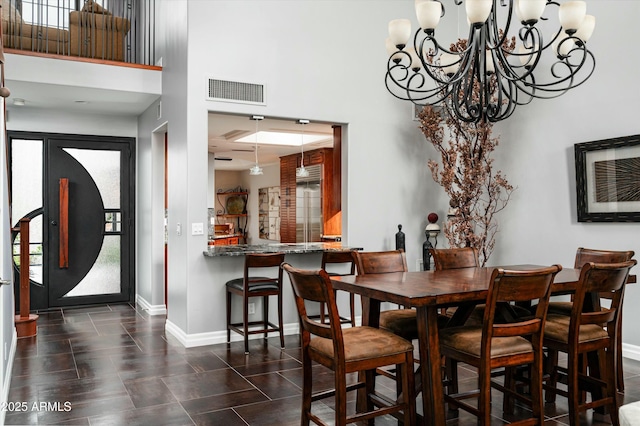 dining room with visible vents, baseboards, a notable chandelier, and a towering ceiling