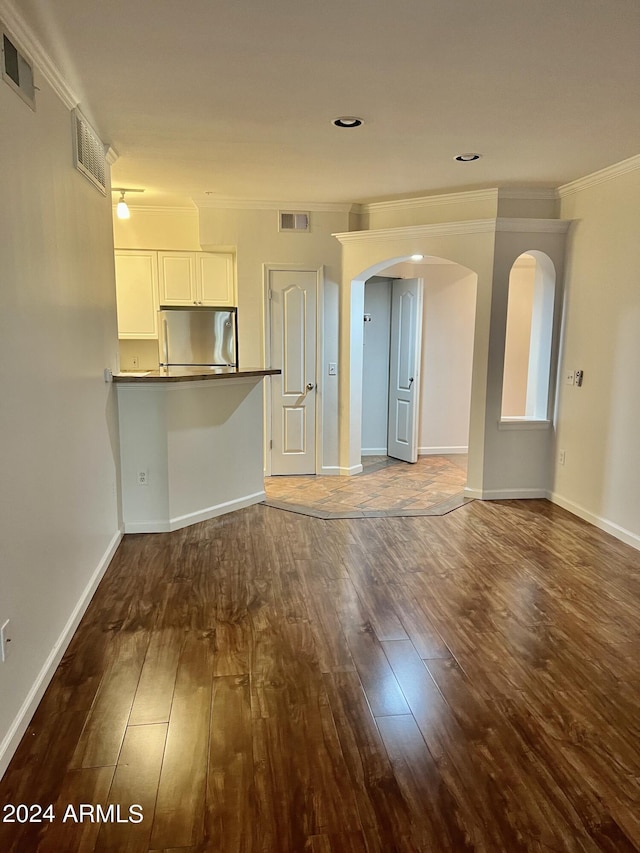 unfurnished living room with crown molding and dark wood-type flooring