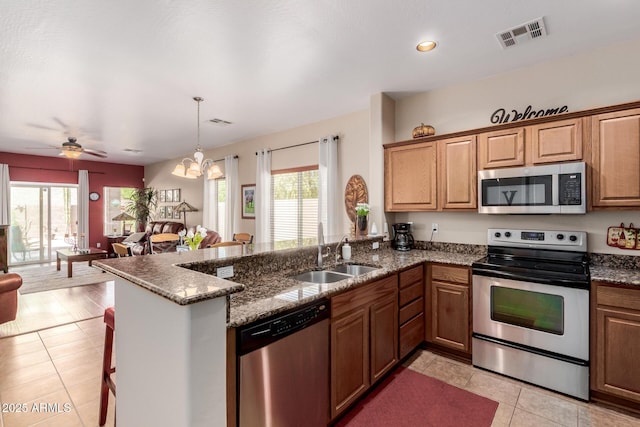 kitchen featuring visible vents, appliances with stainless steel finishes, a sink, a peninsula, and light tile patterned flooring