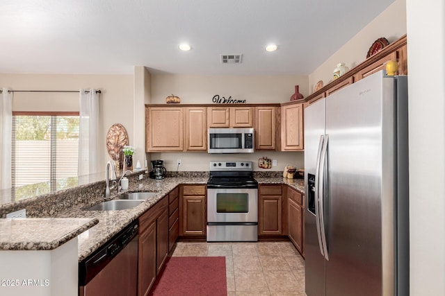 kitchen featuring visible vents, appliances with stainless steel finishes, light stone countertops, a sink, and a peninsula