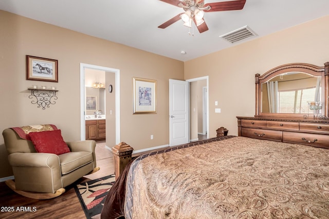 bedroom with ceiling fan, visible vents, wood finished floors, baseboards, and ensuite bathroom
