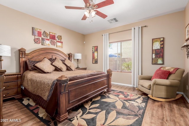 bedroom with visible vents, a ceiling fan, baseboards, and wood finished floors
