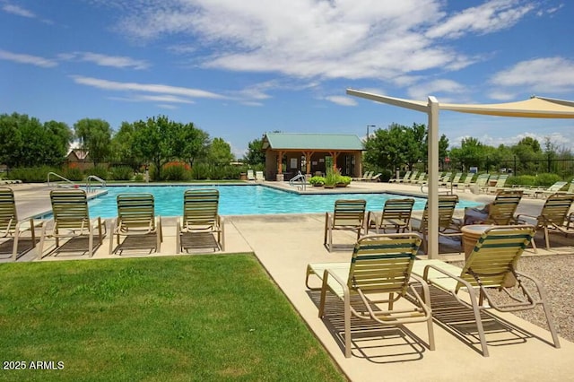 pool with a lawn, fence, and a patio