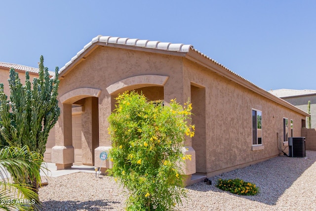 exterior space featuring stucco siding, central AC, and a tiled roof