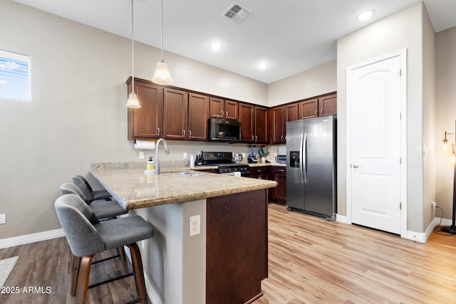 5524 N Brinson Ln, Prescott Valley, AZ 86314 - kitchen with stainless steel appliances, a sink, a peninsula, light wood finished floors, and a kitchen breakfast bar
