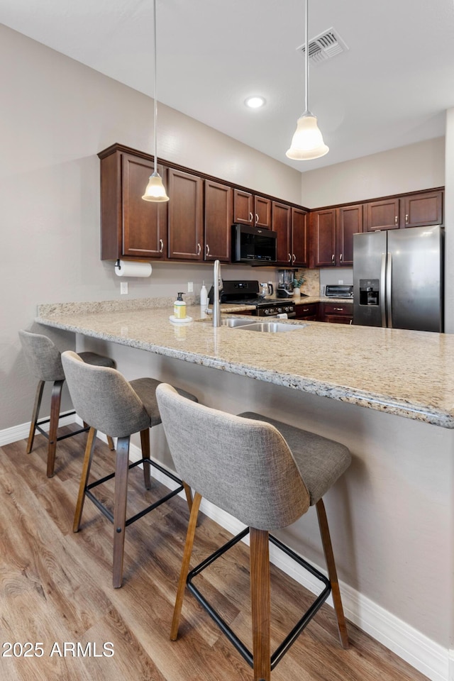 5524 N Brinson Ln, Prescott Valley, AZ 86314 - kitchen featuring stainless steel appliances, baseboards, a peninsula, light wood-type flooring, and decorative light fixtures