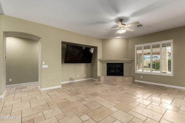 3531 E Norwood Cir, Mesa, AZ 85213 - unfurnished living room with ceiling fan, a tiled fireplace, arched walkways, and stone tile flooring