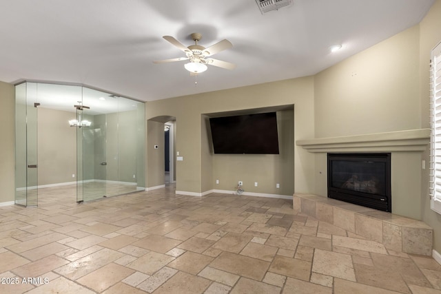 3531 E Norwood Cir, Mesa, AZ 85213 - unfurnished living room featuring a ceiling fan, arched walkways, a chandelier, a fireplace, and stone tile flooring