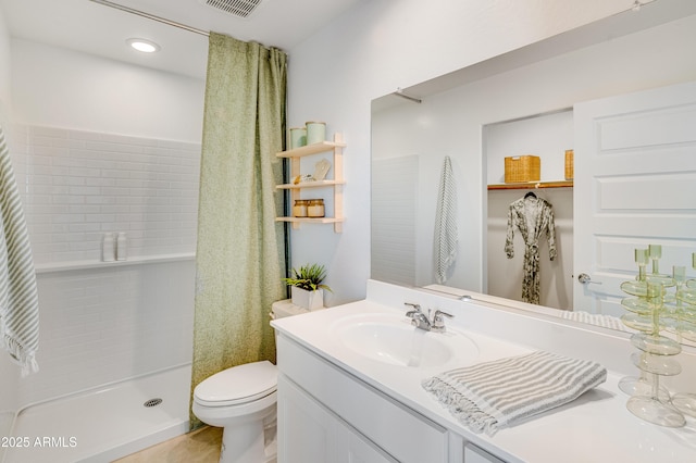 full bathroom featuring toilet, vanity, a stall shower, and visible vents
