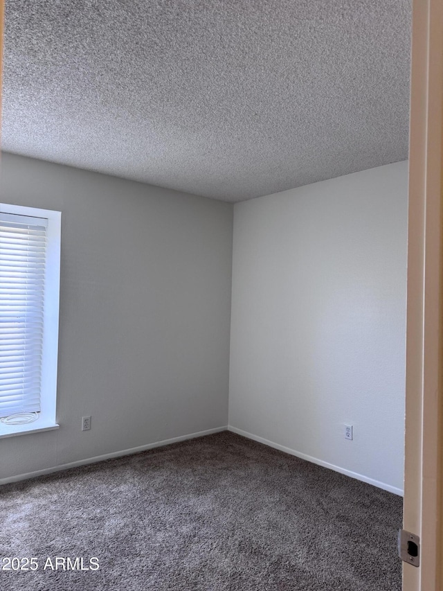 carpeted empty room with a textured ceiling and baseboards