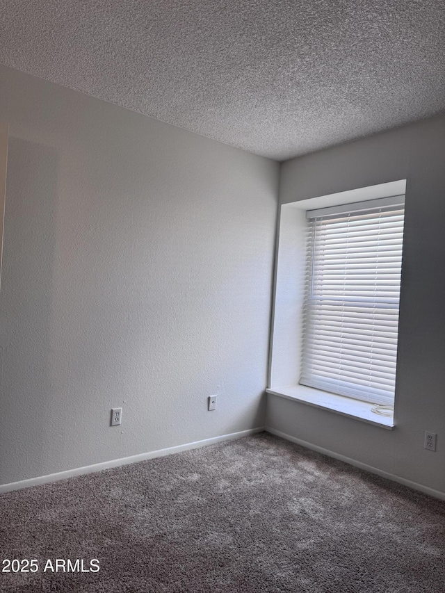 carpeted spare room with a textured ceiling, a textured wall, and baseboards