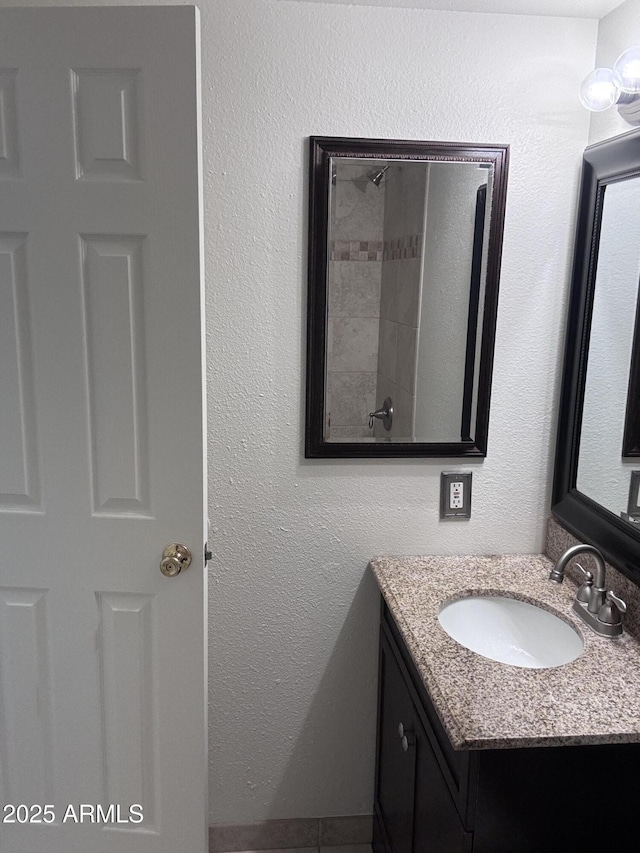 bathroom with a textured wall and vanity