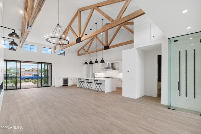 unfurnished living room featuring a high ceiling, light hardwood / wood-style floors, a chandelier, and sink