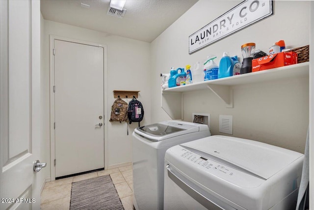 laundry area featuring washing machine and clothes dryer and light tile patterned floors