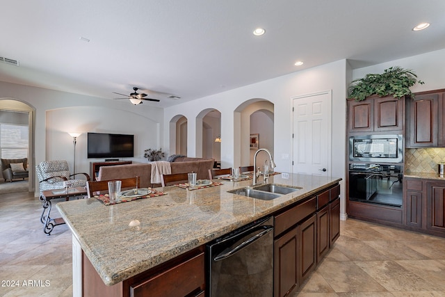 kitchen featuring a kitchen island with sink, dark brown cabinets, black appliances, light stone counters, and sink