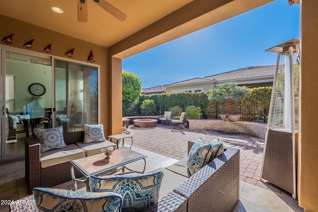 view of patio / terrace with ceiling fan and an outdoor living space with a fire pit