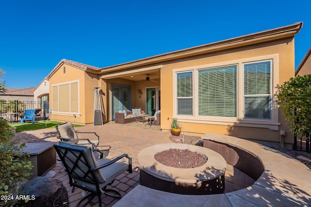 rear view of property with ceiling fan, an outdoor fire pit, and a patio