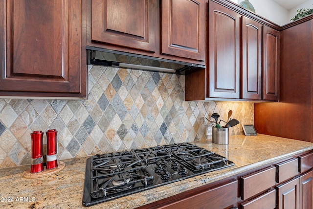 kitchen with light stone countertops, black gas cooktop, ventilation hood, and tasteful backsplash