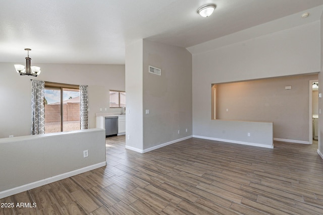 empty room featuring a notable chandelier, vaulted ceiling, sink, and wood-type flooring