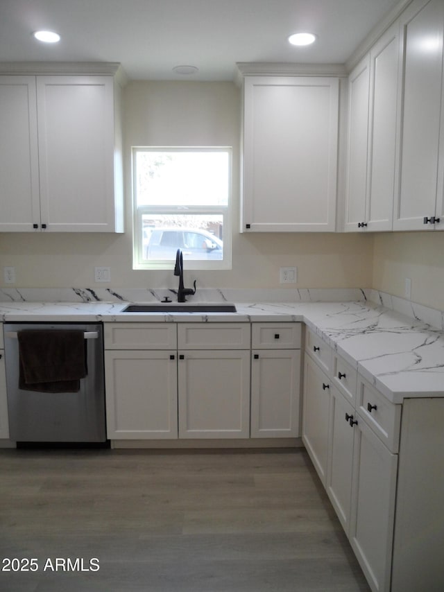 kitchen with sink, stainless steel dishwasher, white cabinets, and light hardwood / wood-style flooring