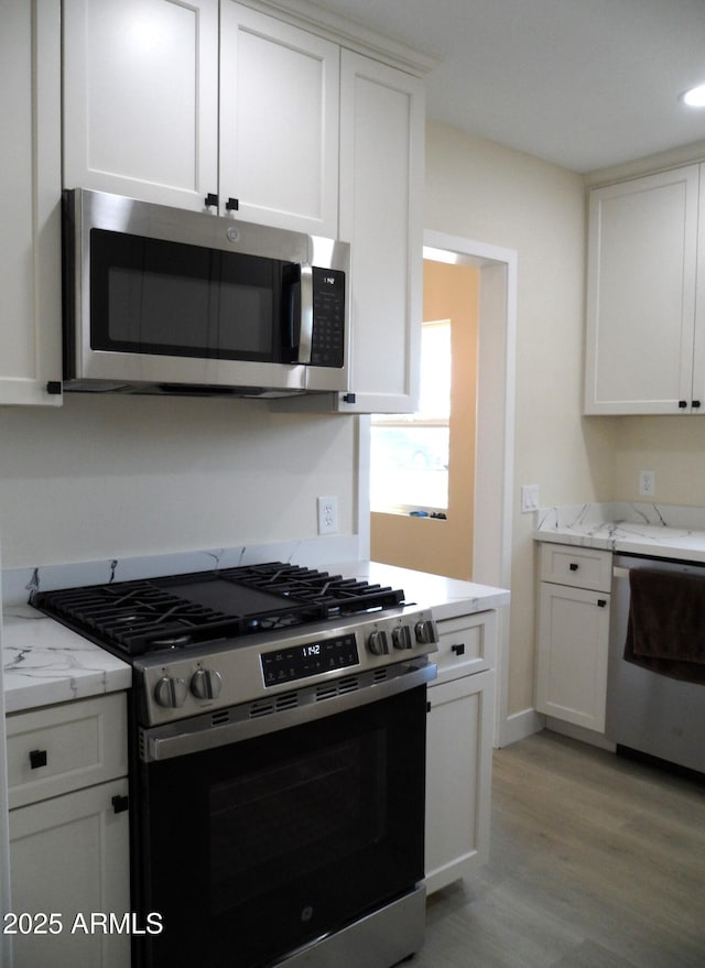 kitchen with white cabinetry, stainless steel appliances, and light stone counters