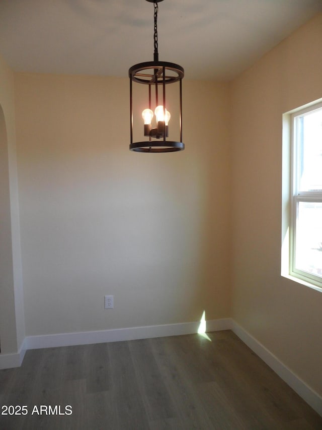 spare room with dark wood-type flooring and a notable chandelier