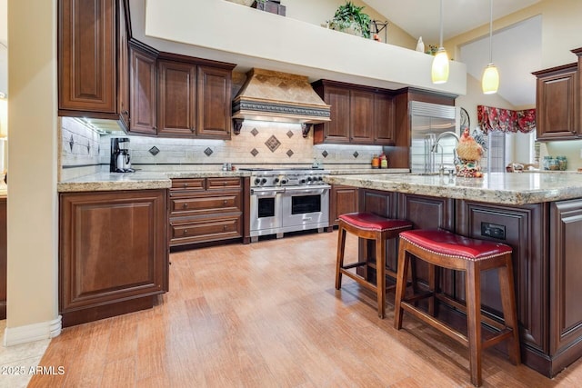 10434 N 44th St N, Phoenix, AZ 85028 - kitchen featuring premium appliances, wall chimney exhaust hood, tasteful backsplash, a kitchen breakfast bar, and high vaulted ceiling