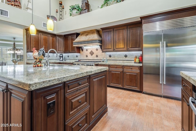 10434 N 44th St N, Phoenix, AZ 85028 - kitchen with appliances with stainless steel finishes, custom range hood, a sink, decorative light fixtures, and light wood-style floors
