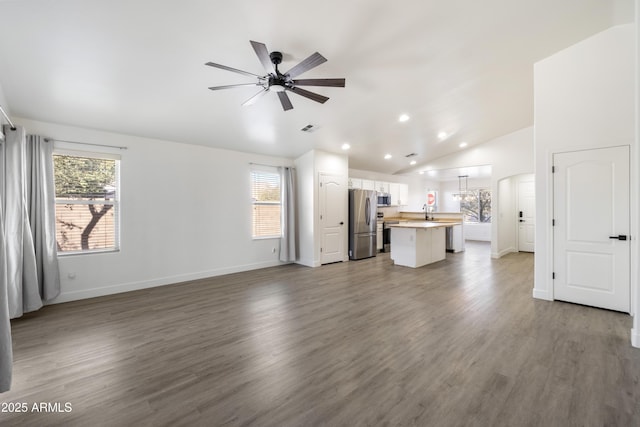 unfurnished living room with ceiling fan, sink, hardwood / wood-style floors, and vaulted ceiling